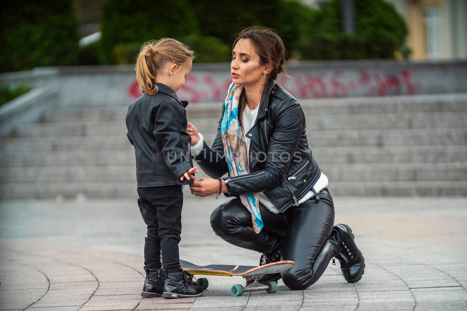 mom with daughter and skate on the background of the city