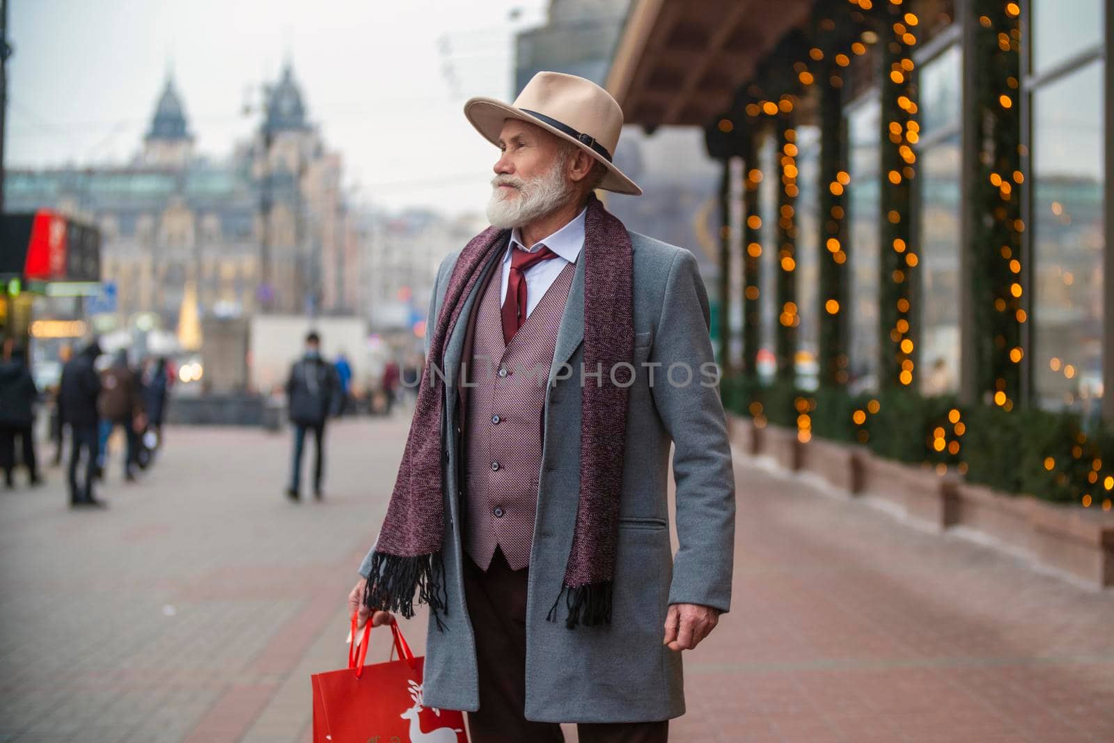 bearded grandfather with a handbag walks on the street