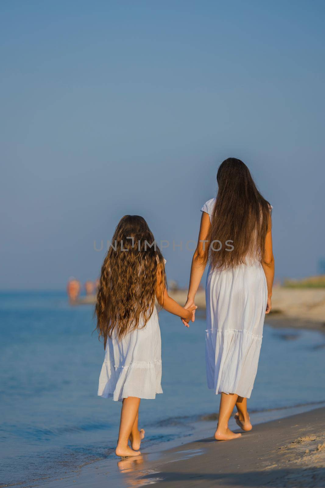 mom and daughter walk on the beach by zokov