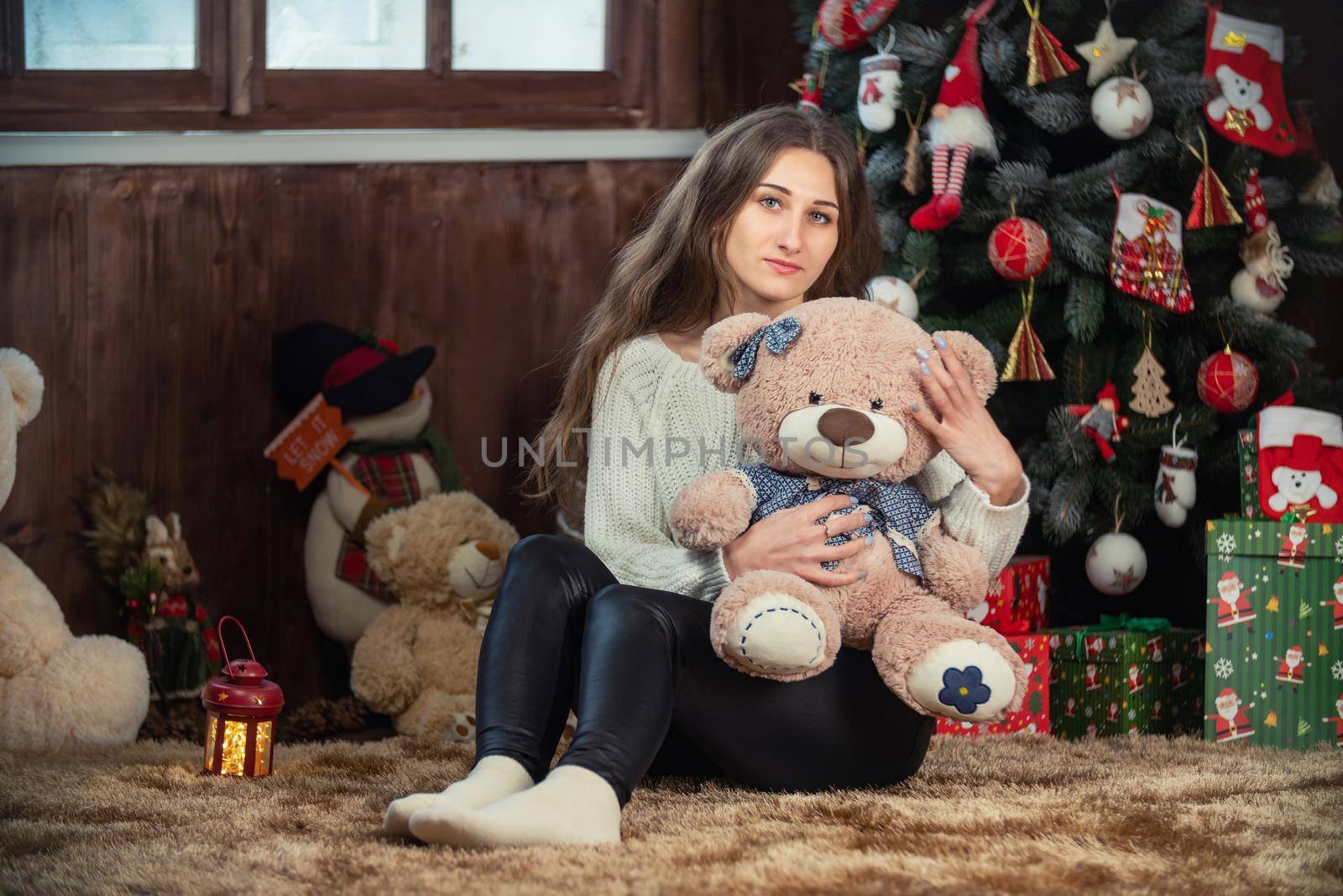 girl with a teddy bear on the background of a christmas tree