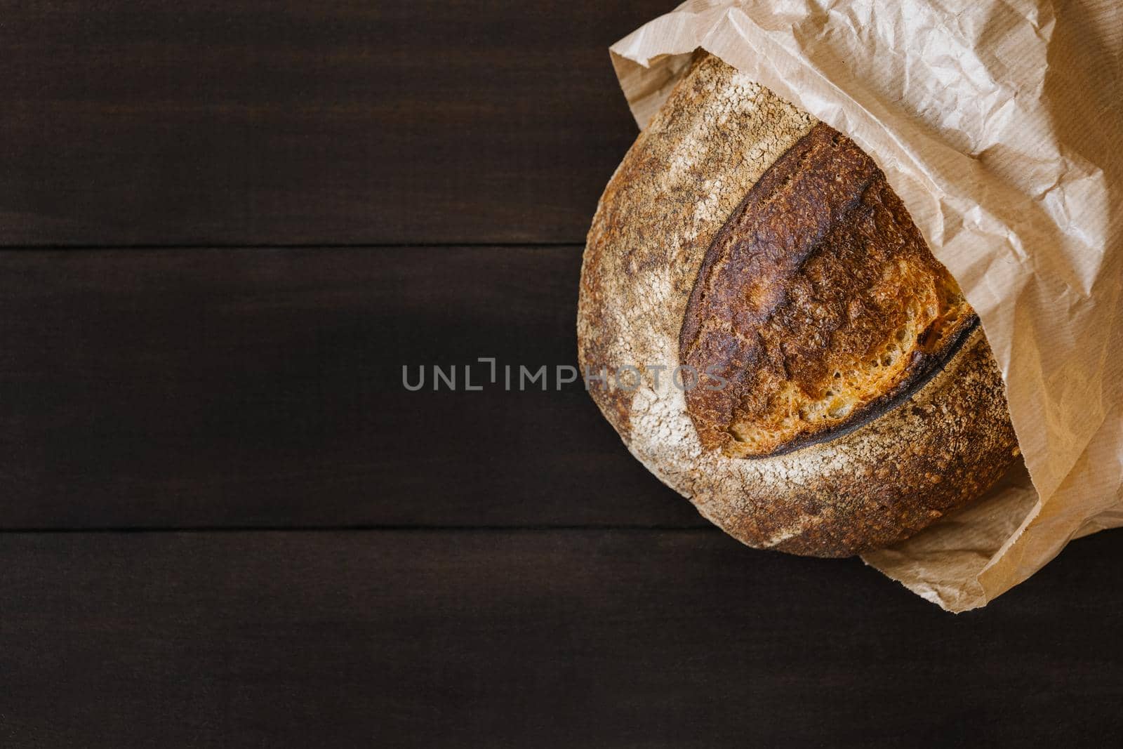 Fresh homemade wheat bread on wooden table in paper bag. Flat lay, top view, copy space concept