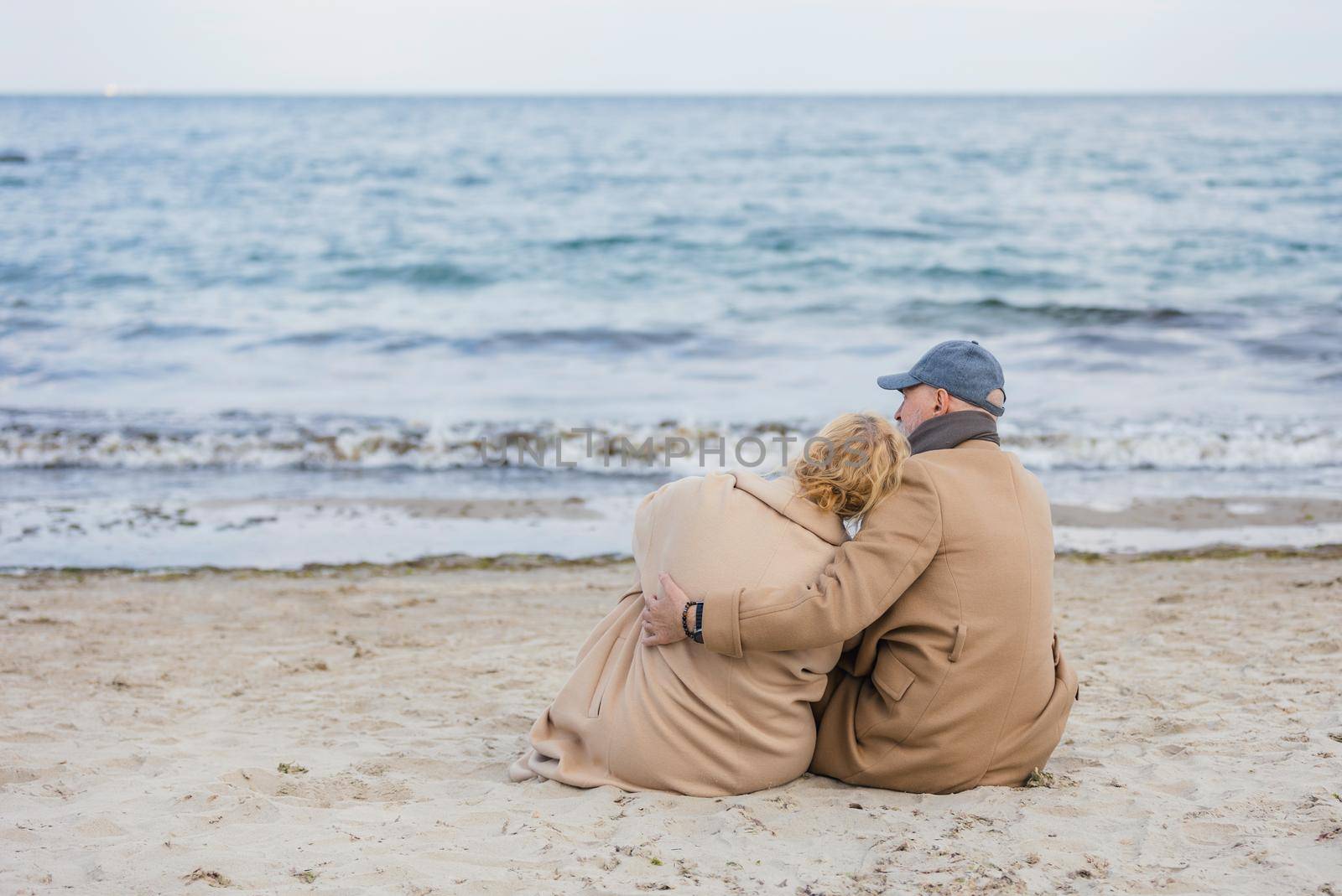 aged couple sitting on the beach by zokov