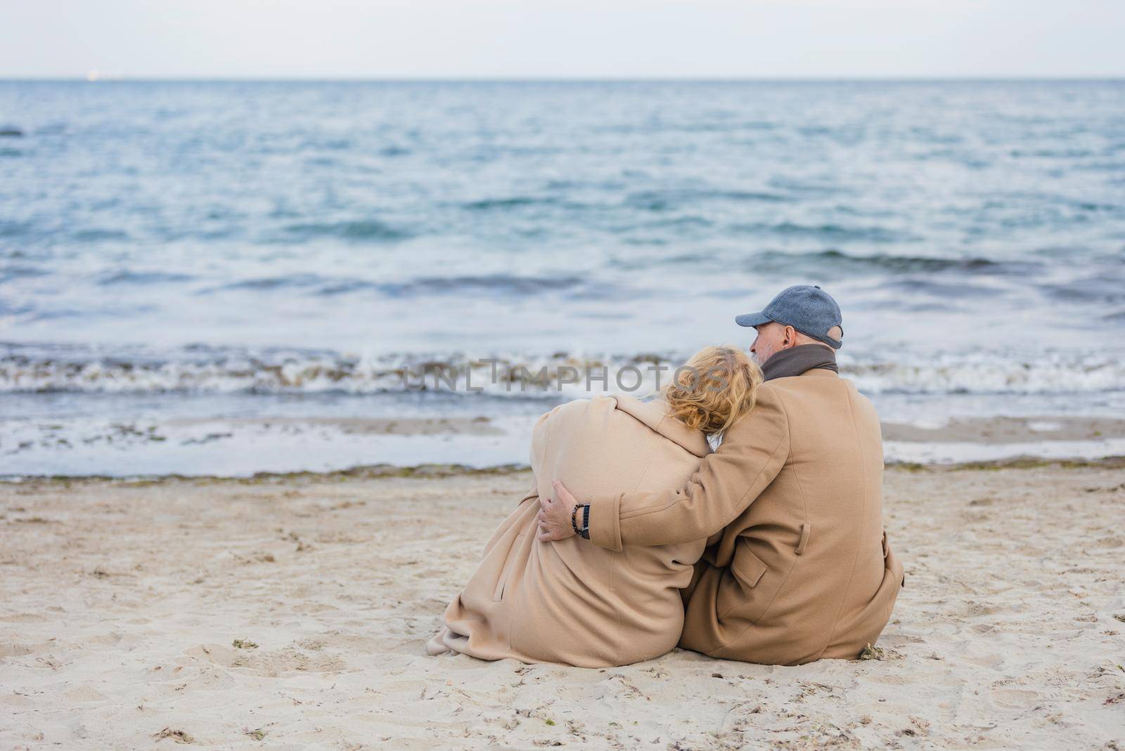 aged couple sitting on the beach near the sea