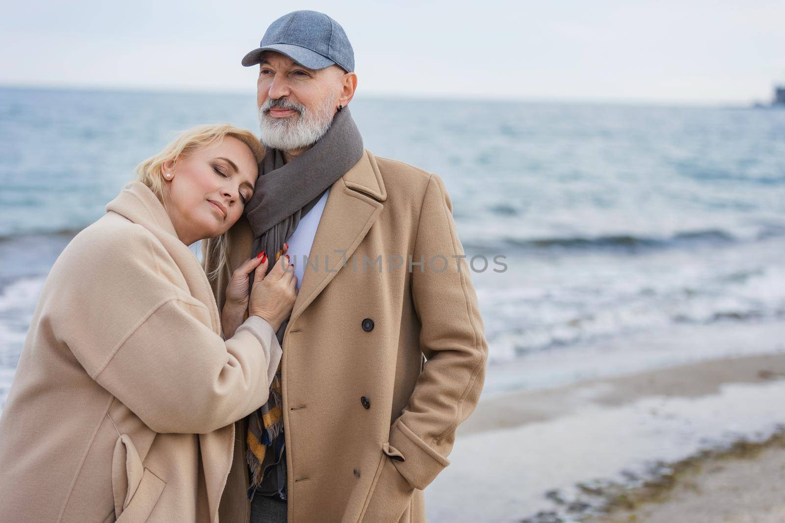 Aged couple walking along the beach against the background of the sea