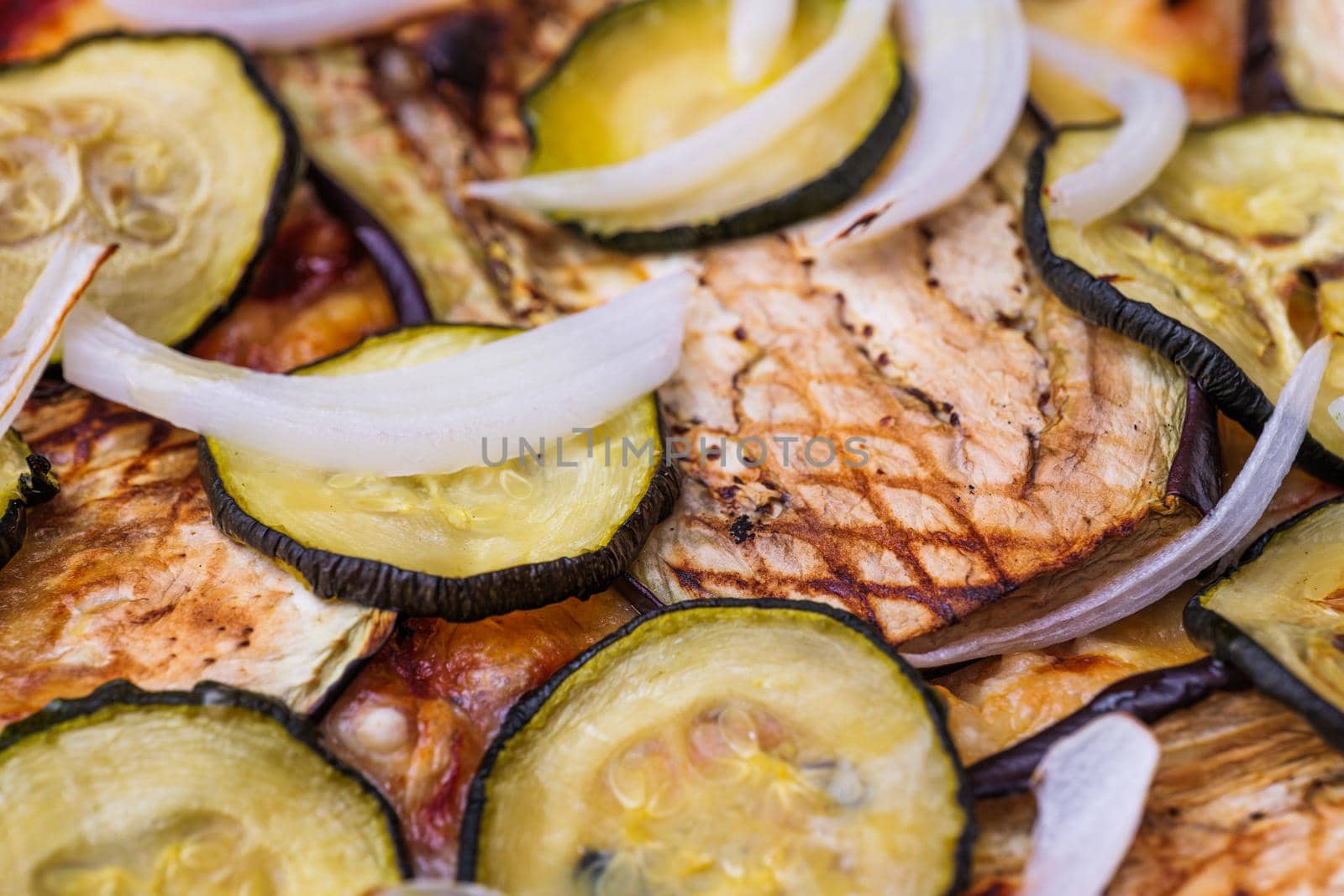 Close-up of pizza topped with grilled eggplant, zucchini and onion. Macro shot of delicious products. by apavlin