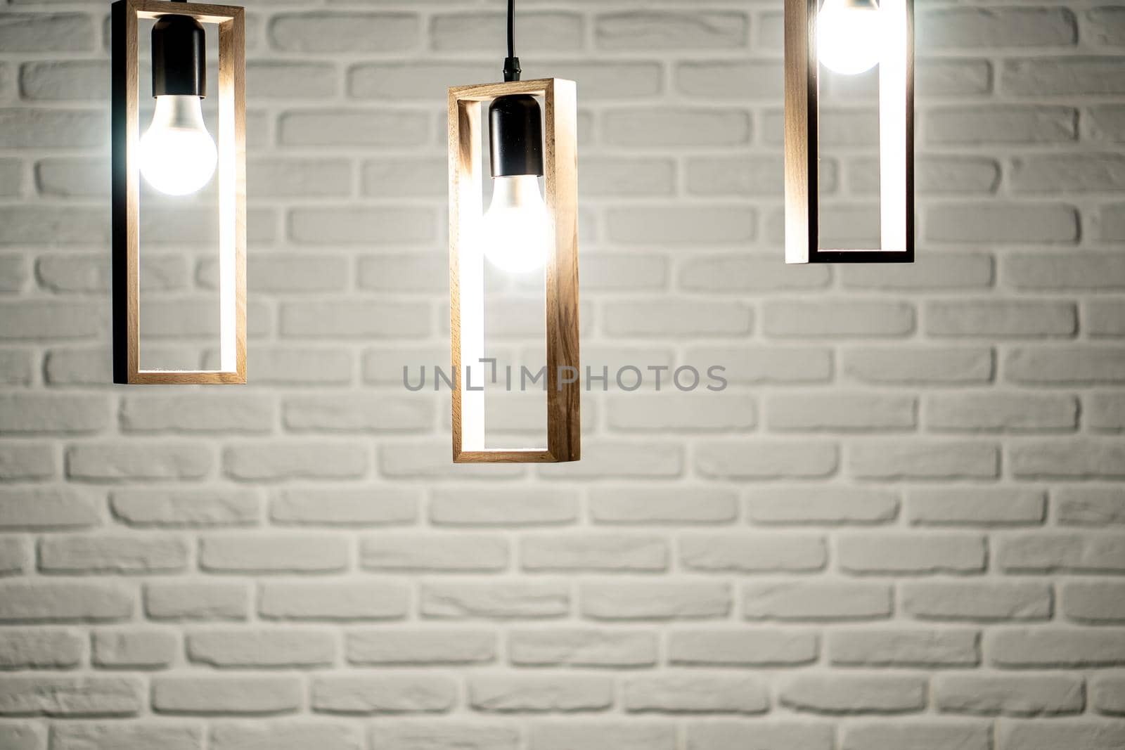 Three lamps on a background of a white brick wall. Three light bulbs on a white brick background. White brick background with three swirls that hang from above