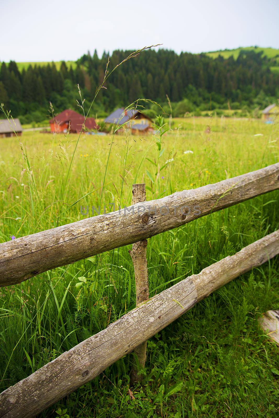 Wooden fence against the summer landscape in the Ukrainian Carpathian Mountains.