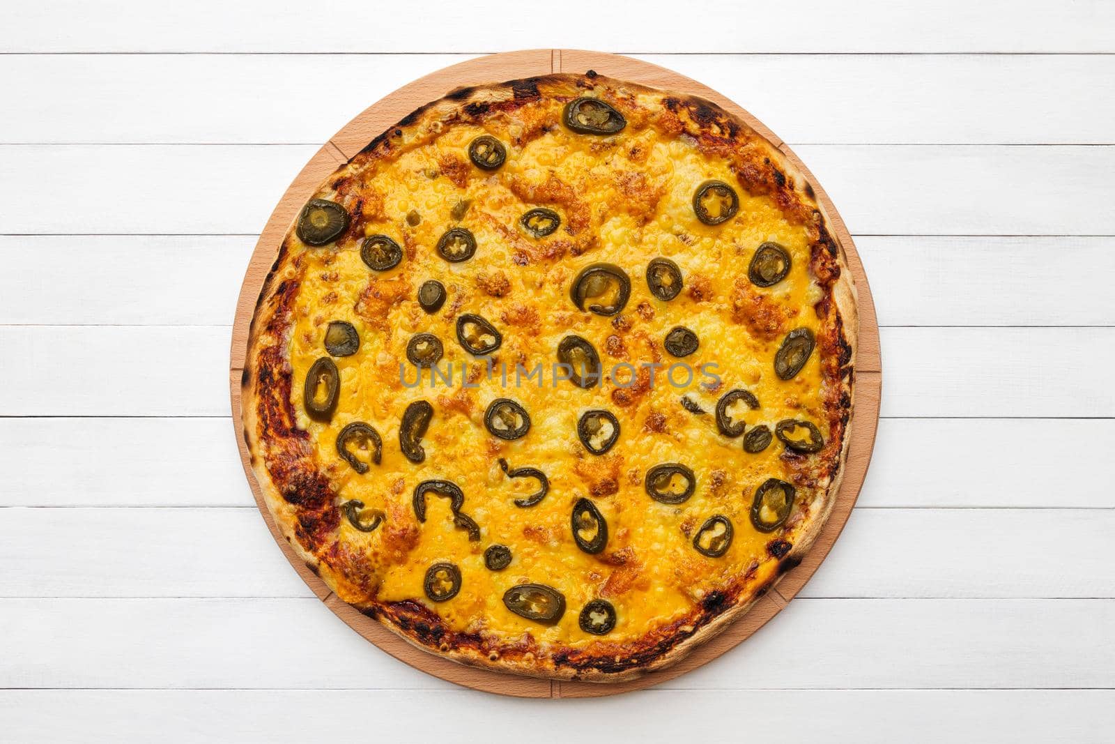 Whole round pizza topped with olives and cheese on wooden plate. Top view on white board background. Copy space.