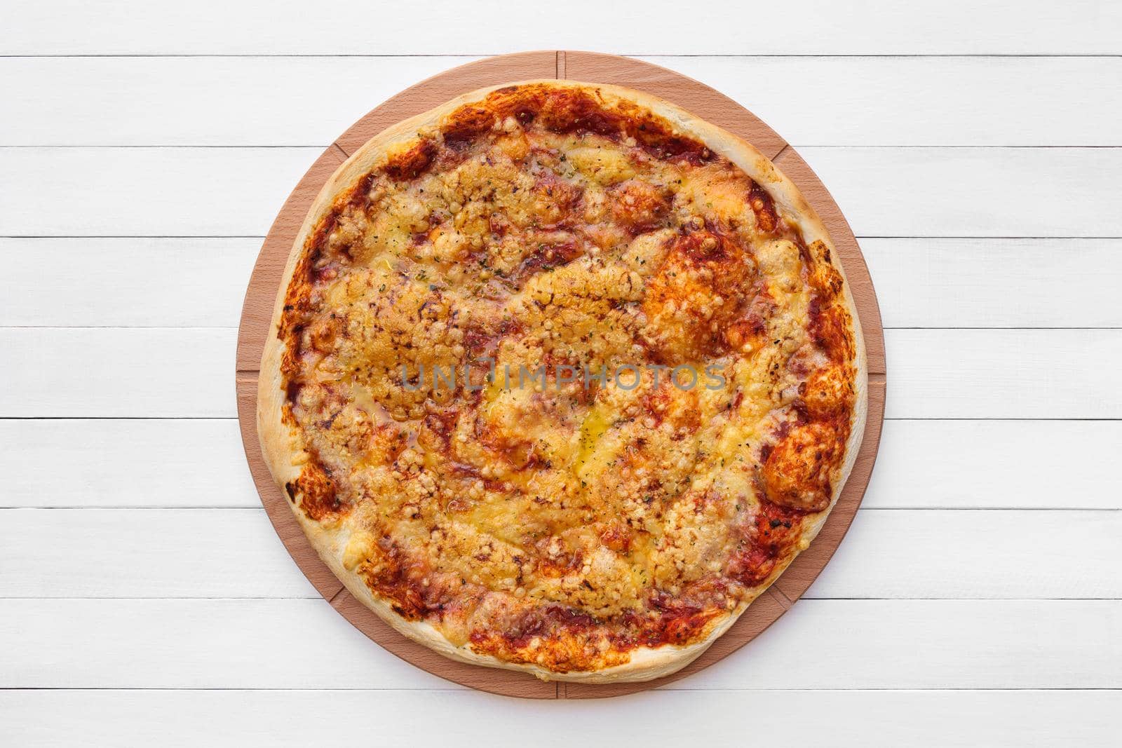 Whole round pizza topped with cheese and oregano on wooden plate. Top view on white board background. Copy space.