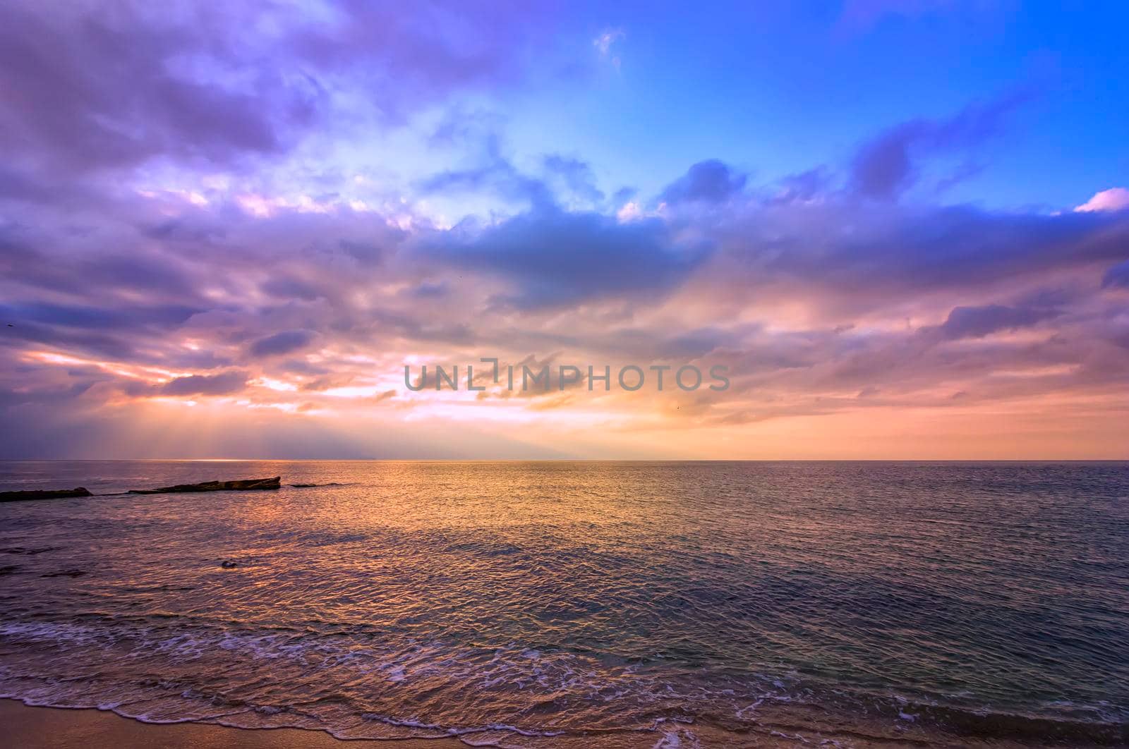 Amazing scenic view of colorful sky with sun rays over the sea.