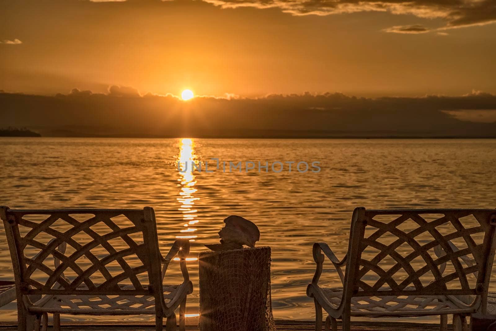 A couple of deck chairs at sunrise on the sea beach.
