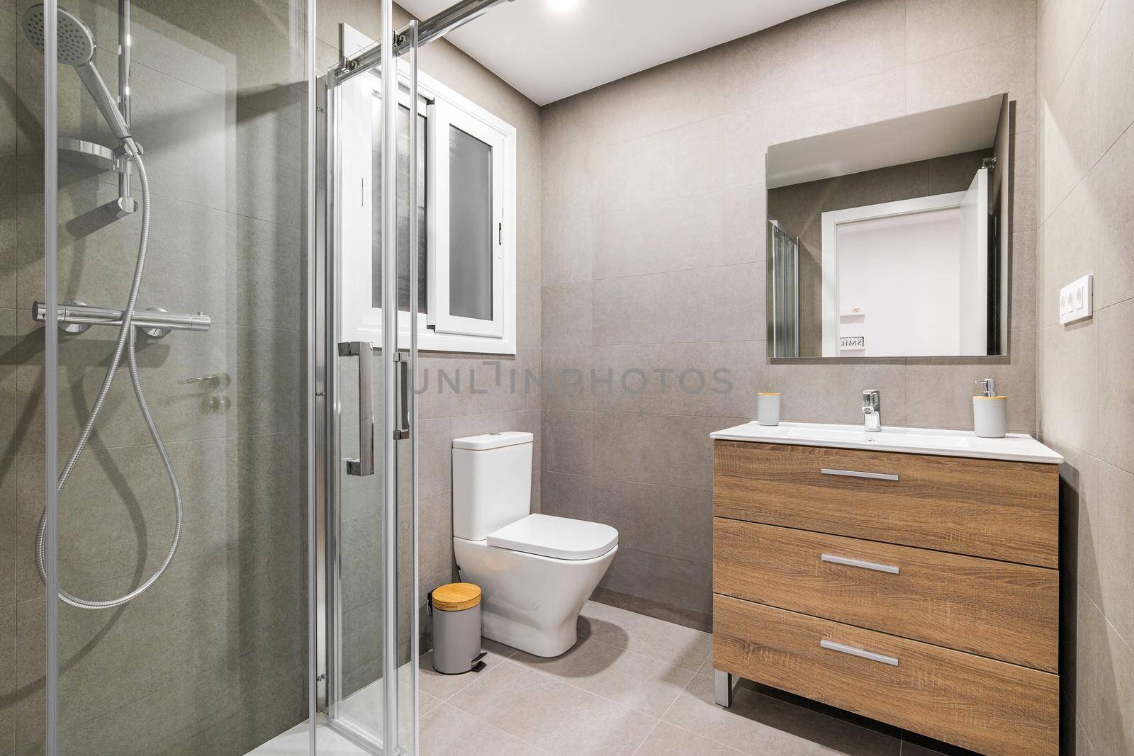 Modern refurbished bathroom with shower zone, toilet, wooden base with white sink and mirror. by apavlin
