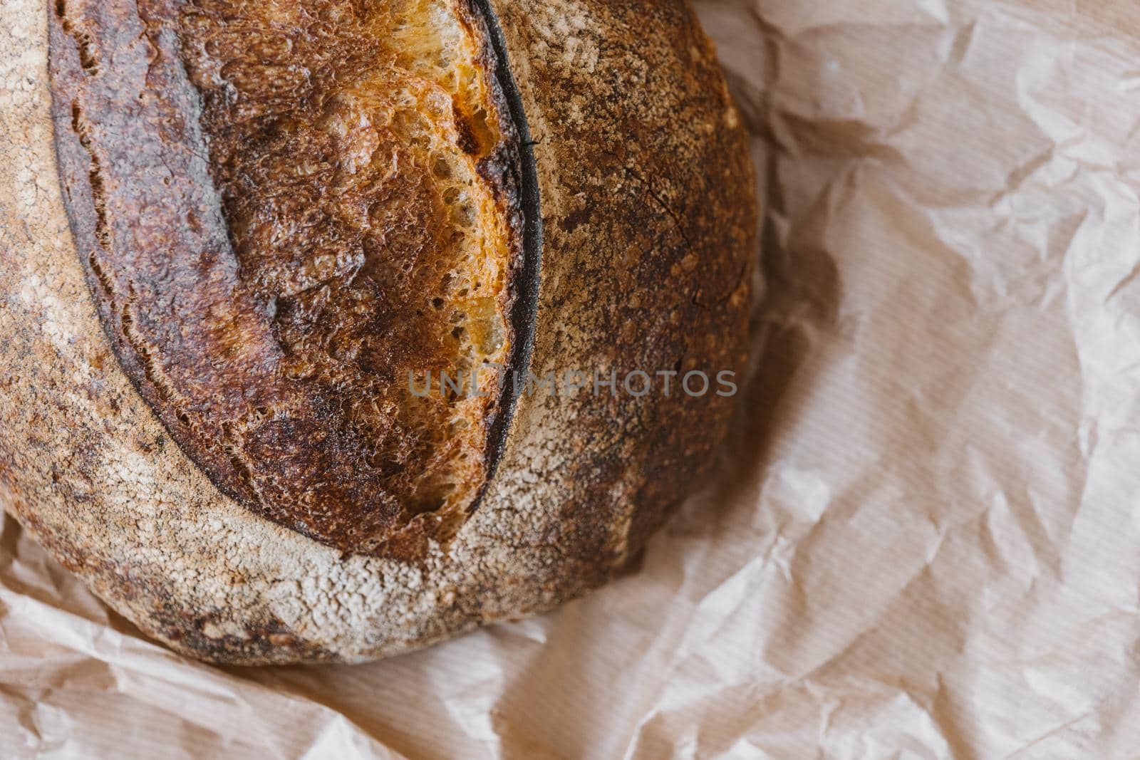 Close-up of homemade wheat bread on paper bag. Top view of crispy baked bread surface texture. Selective focus