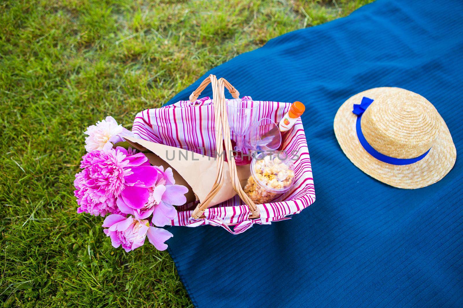 A basket with beautiful flowers and a straw hat on a plaid