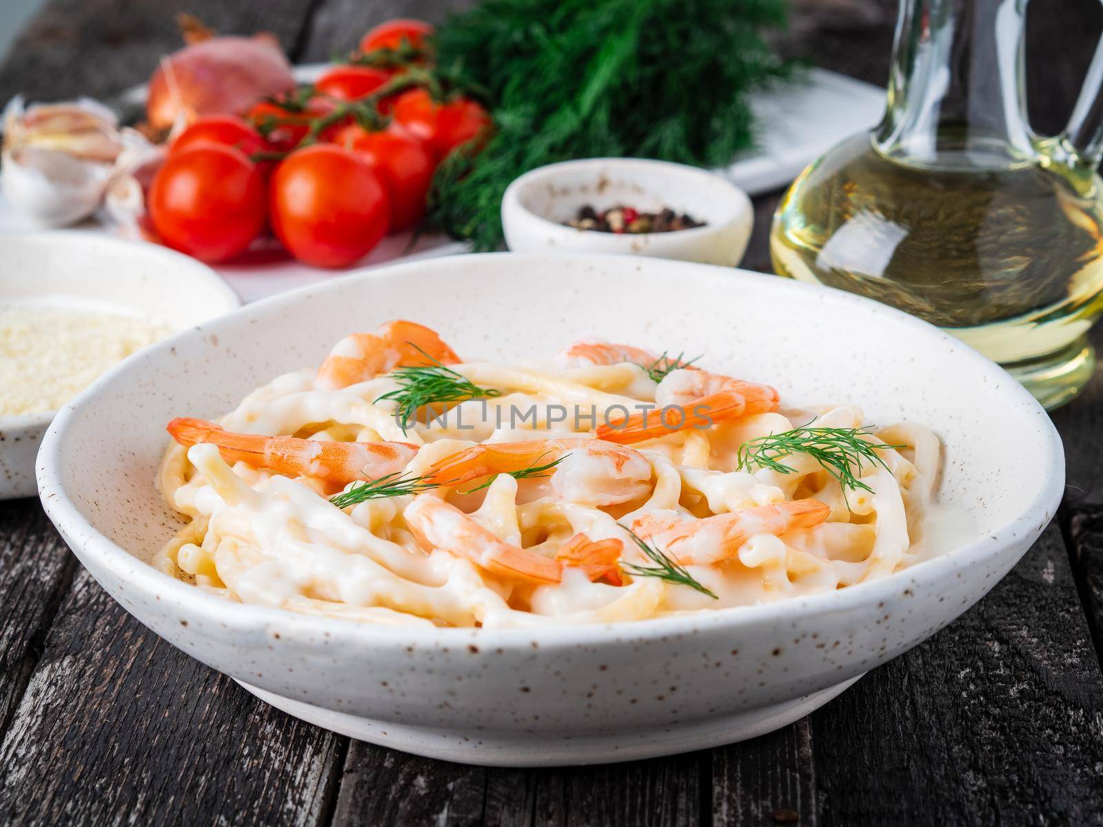 italian pasta spaghetti with shrimps, bechamel sauce and chopped dill on dark rustic wooden table, side view.