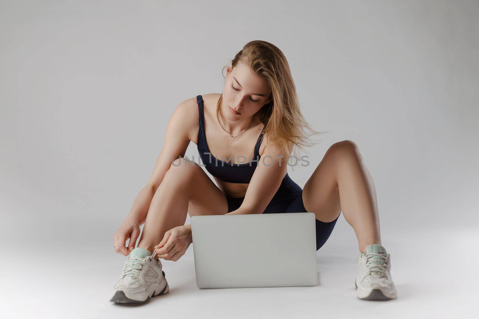 girl posing in the Studio performing exercises online on a laptop on a white background