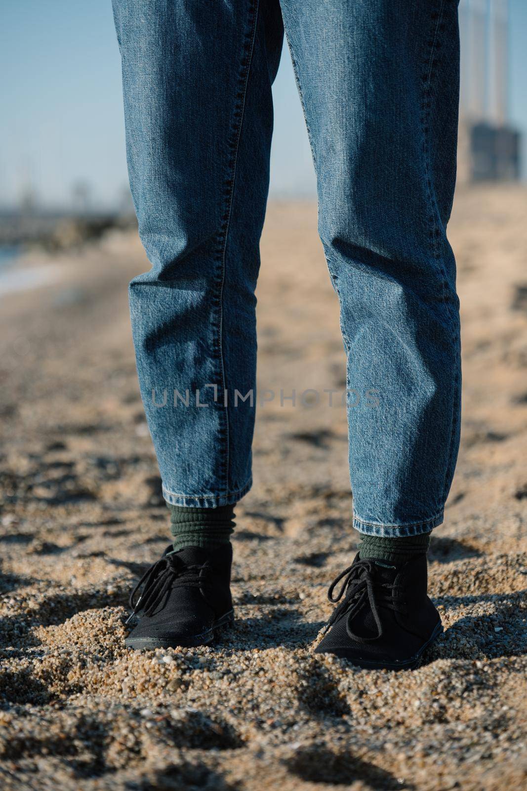 Legs of woman in jeans on sand at a beach. Walking in comfortable shoes on beach. by apavlin