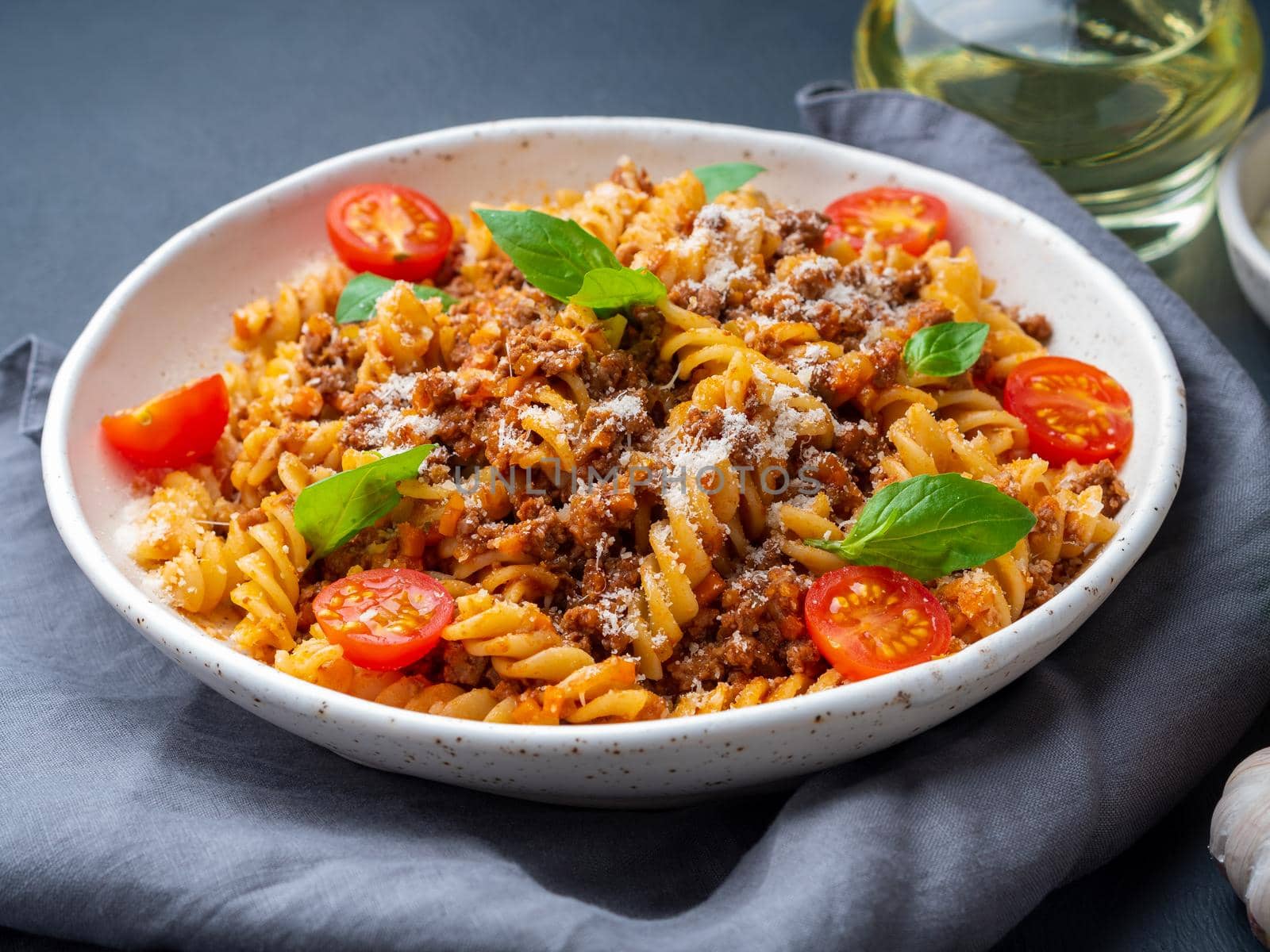 Bolognese pasta. Fusilli with tomato sauce, ground minced beef, basil leaves. Traditional italian cuisine. Side view.