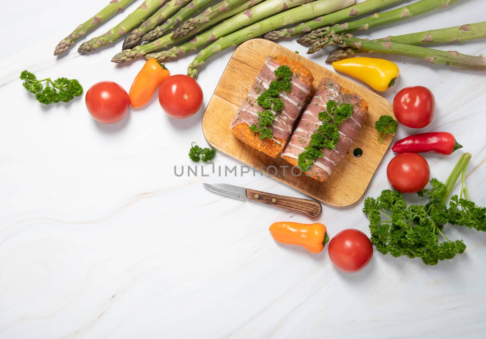 minced meat sausages in bacon with green parsley and fresh vegetables, cherry tomatoes, bell peppers, multicolor food flat lay. High quality photo