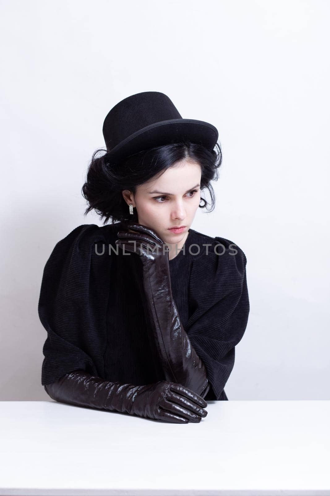a woman in a hat and long gloves sits at a table. High quality photo