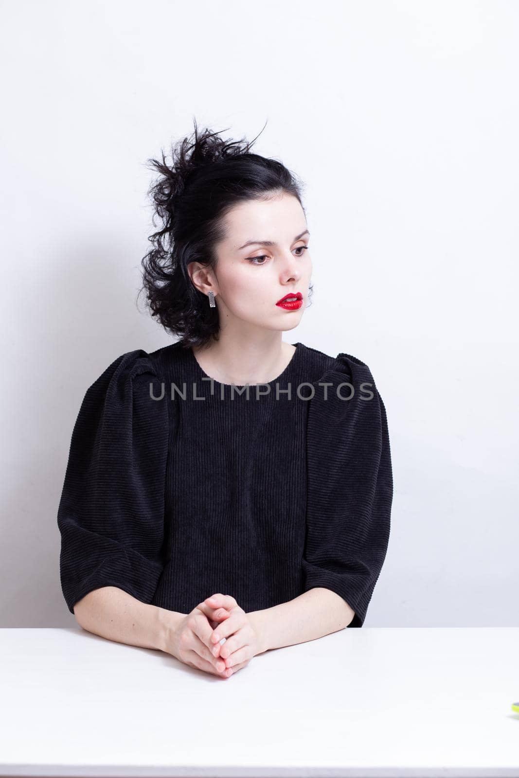 a woman with red lips, curly hair sits at a table. High quality photo