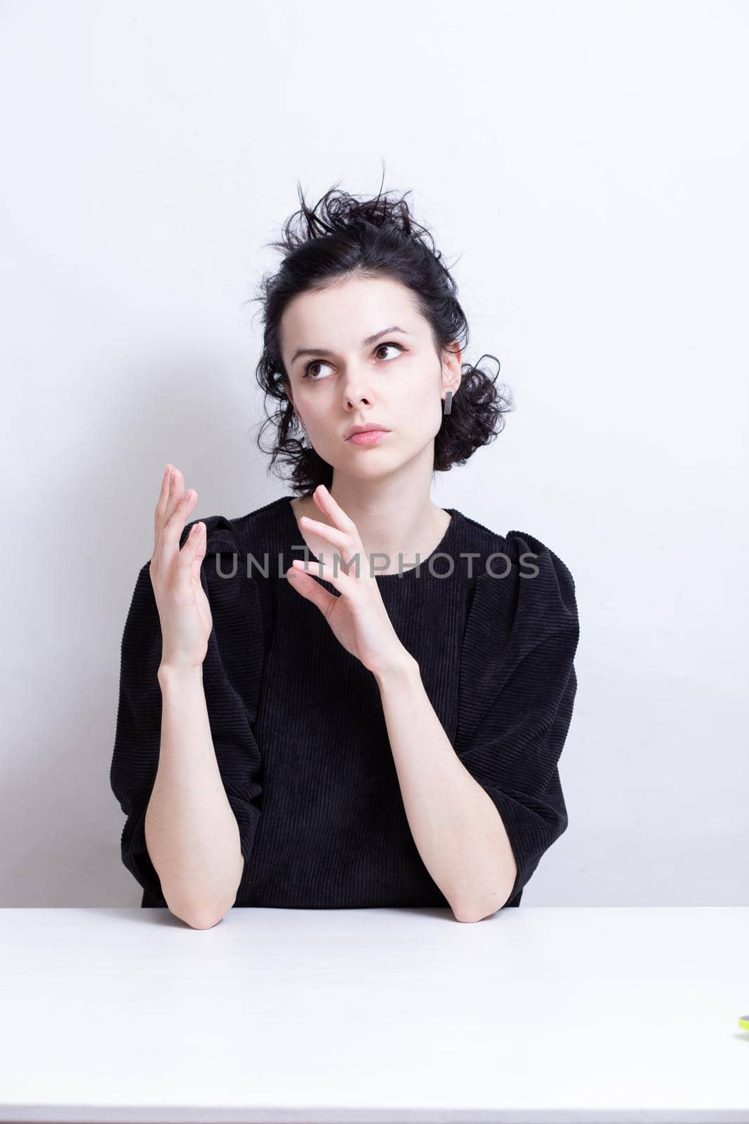 woman with curly hair in a black dress sits at a table. High quality photo