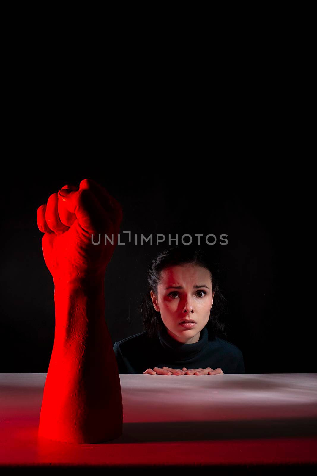 woman afraid of red hand, symbol of dictatorship, black background. High quality photo