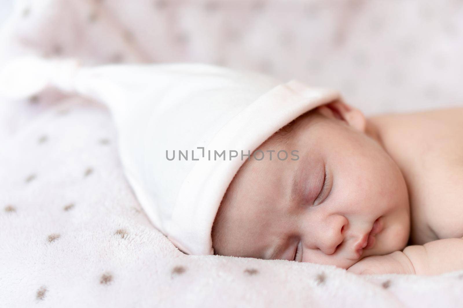 Childhood, care, motherhood, health, medicine, pediatrics concepts - Close up Little peace calm naked infant newborn baby girl in pink hat sleeps resting take deep nap laying on tummy on soft bed