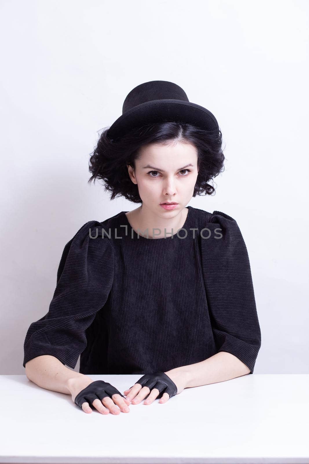 A woman in a hat and fingerless gloves sits at a table by shilovskaya