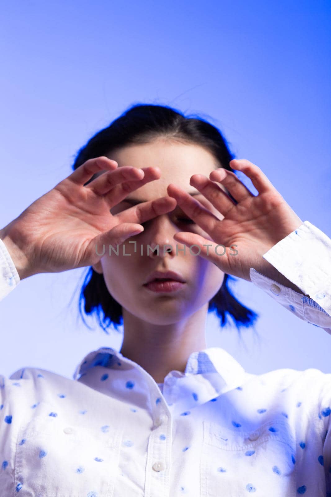 brunette woman in a white shirt with polka dots, on a blue background. High quality photo