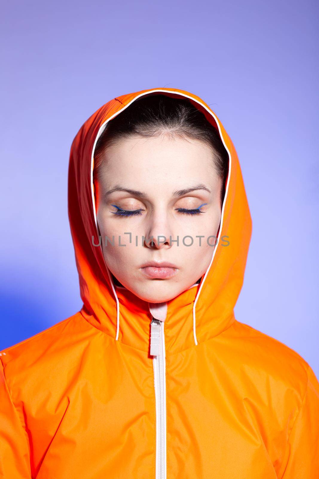 brunette woman in orange jacket, blue background. High quality photo