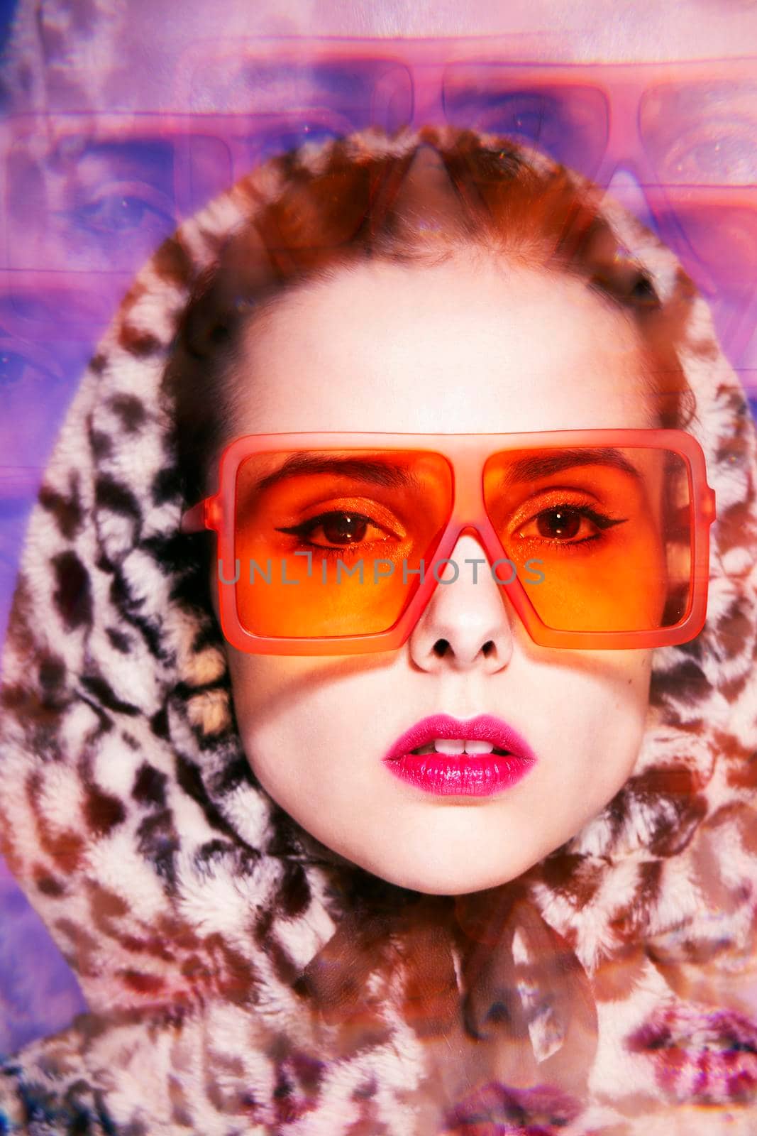 fashionable woman with pink lipstick on her lips in orange glasses and leopard hood. High quality photo