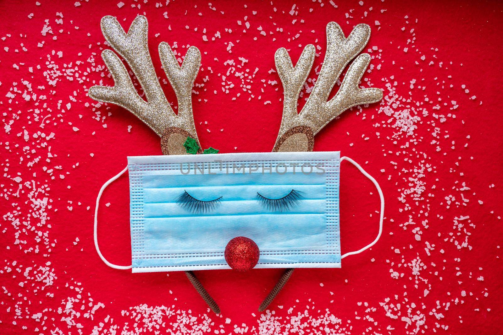 Medical mask with Christmas decoration on a red background. by Matiunina