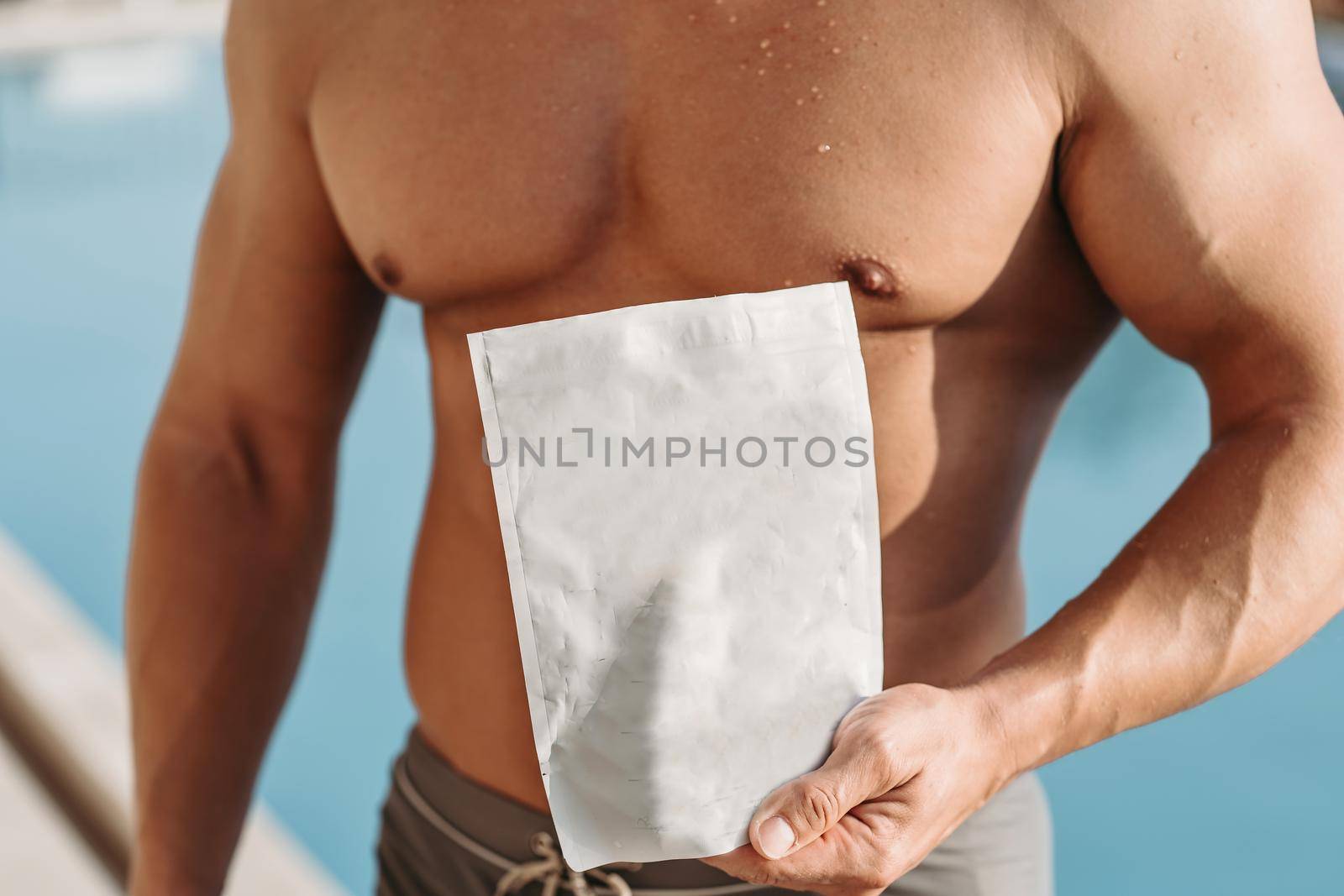 Athlete with large muscles holds a pack of sports nutrition by Praximon