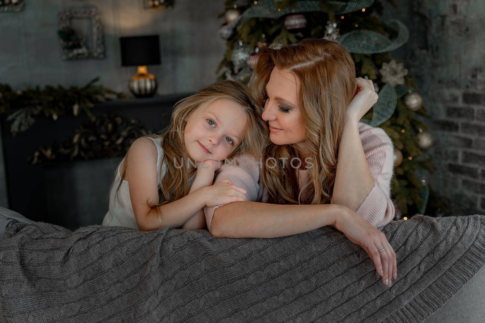 Head shot portrait beautiful young mother embrace little daughter supporting and caring sitting in living room at home spend time together