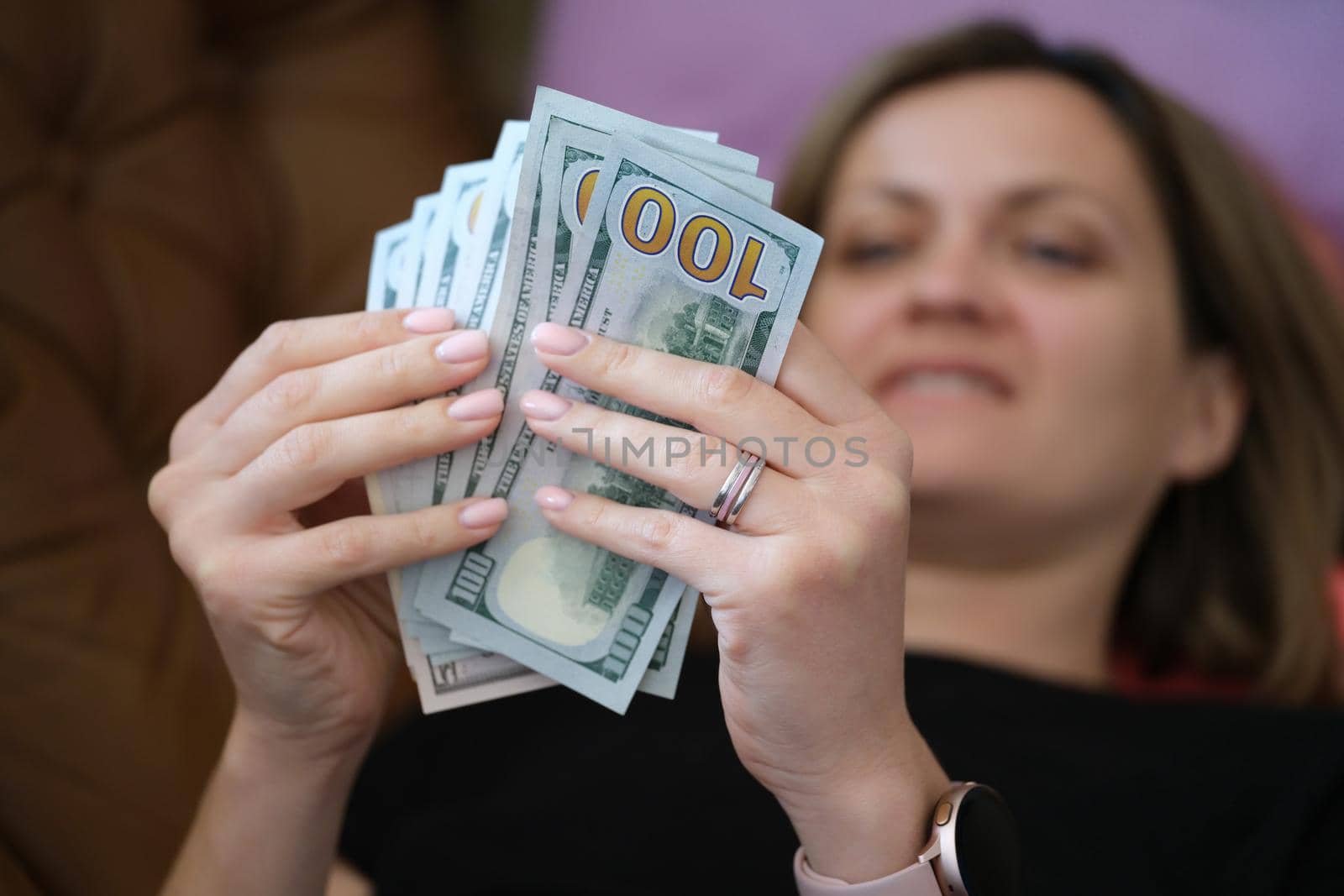 Close-up of happy smiling woman counting money at home. Cheerful female holding cash in hands. Business, finances and increase income concept
