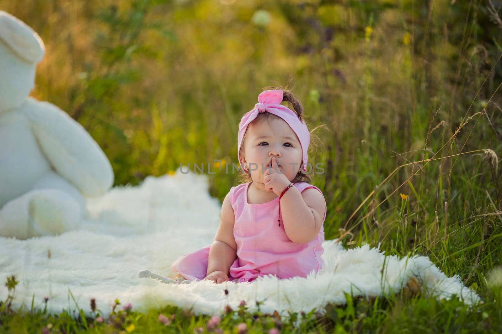 girl in a pink dress sitting on a blanket