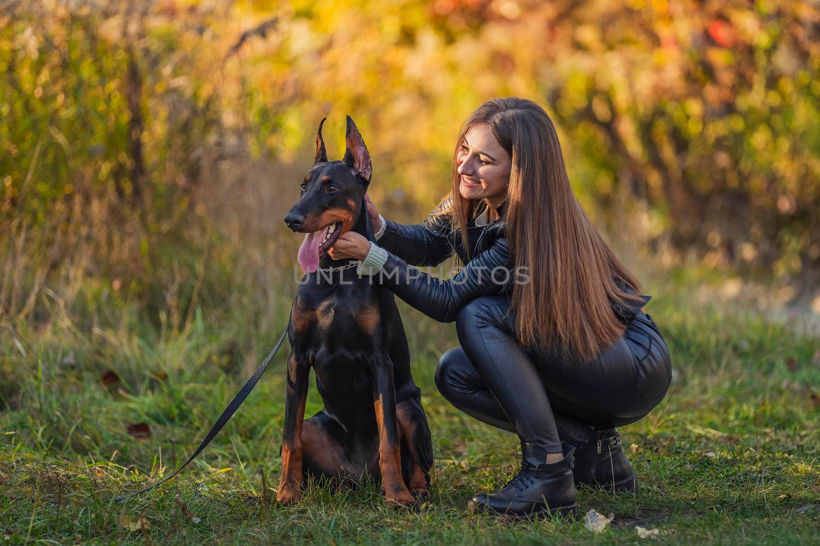 girl sitting near a doberman dog breed in nature