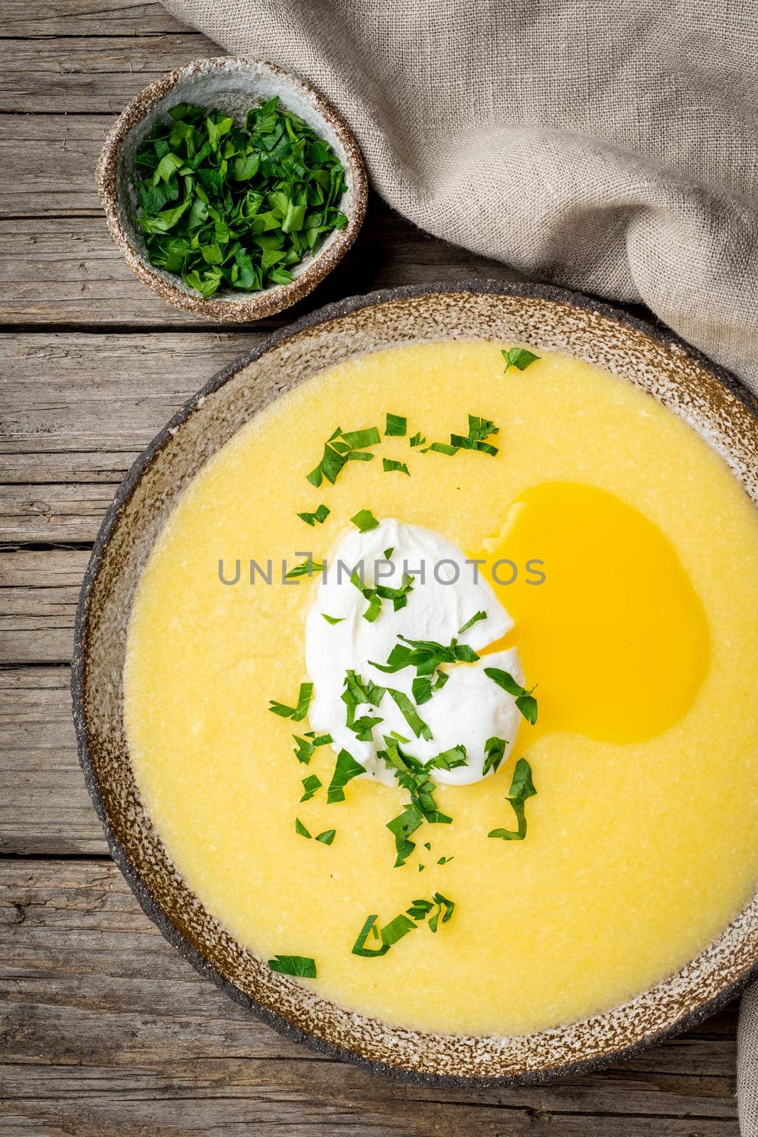 Polenta, porridge with Parmesan cheese and poached egg, vertical on old dark wooden background, top view. traditional Italian cuisine