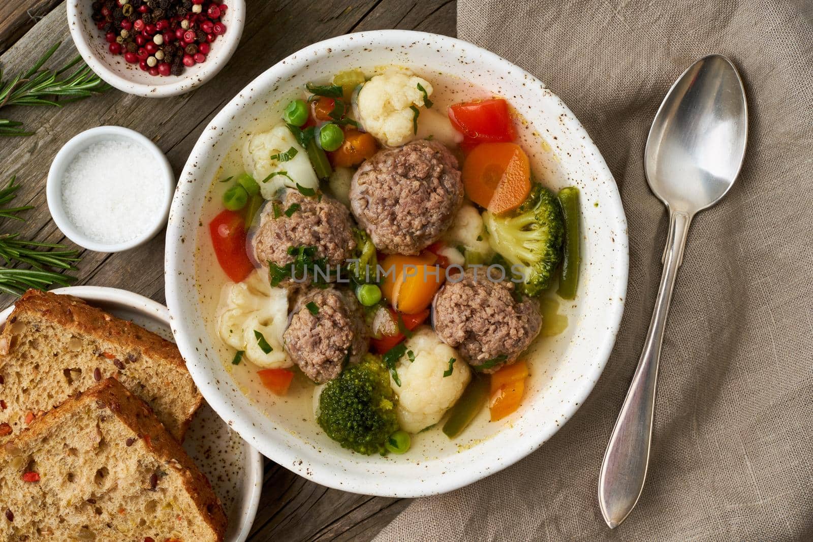 meatballs soup in white plate on old wooden rustic grey table, top view