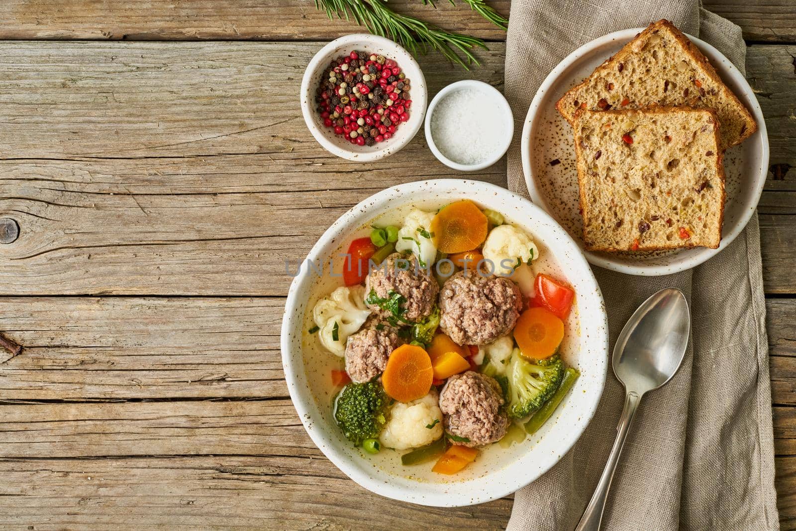 meatballs soup in white plate on old wooden rustic grey table, top view