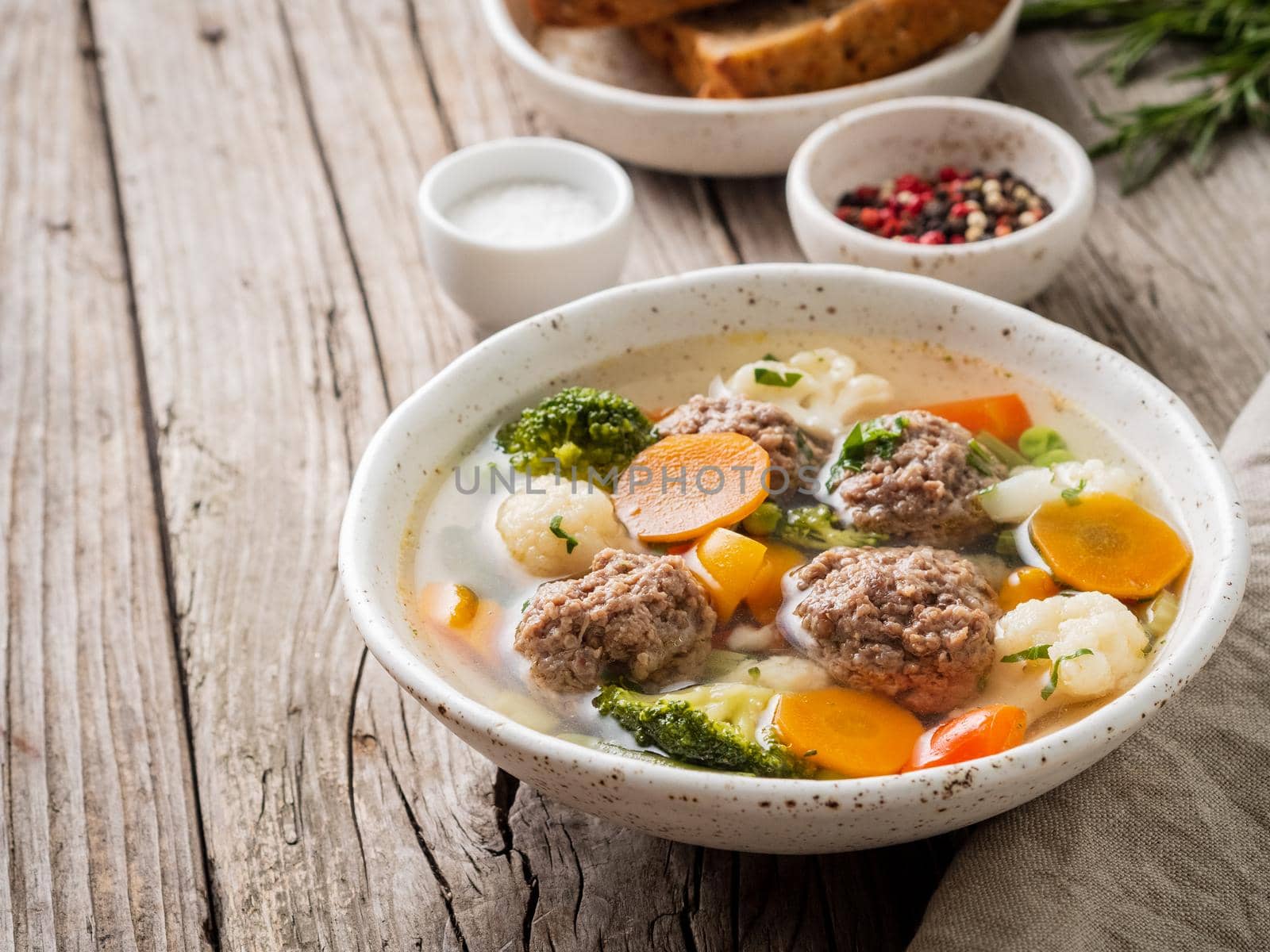 meatballs soup in white plate on old wooden rustic grey table, side view