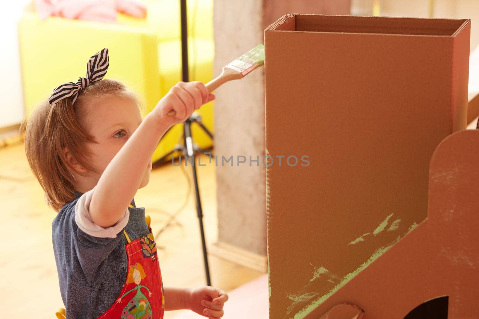 Side view of girl drawing on carton house and having fun at home