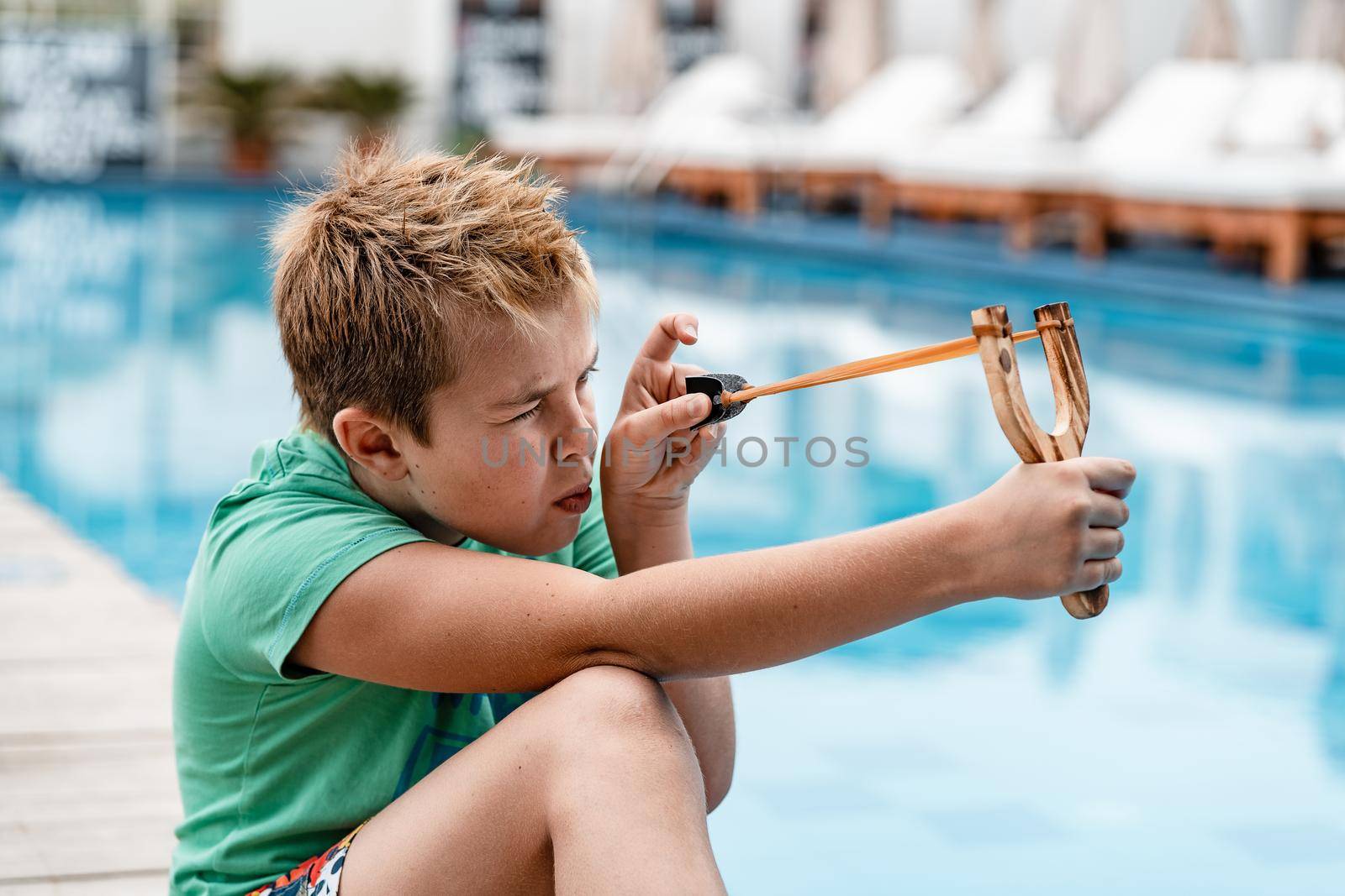 A boy shoots a slingshot near the pool by Praximon