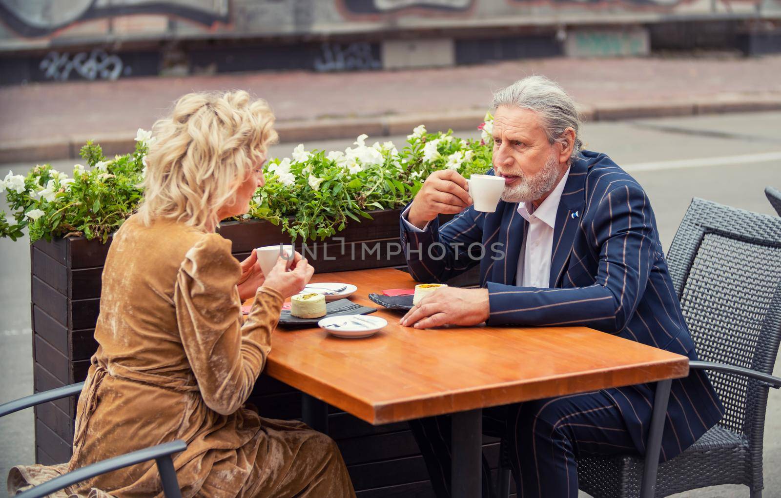 elderly couple sitting at a table on the street