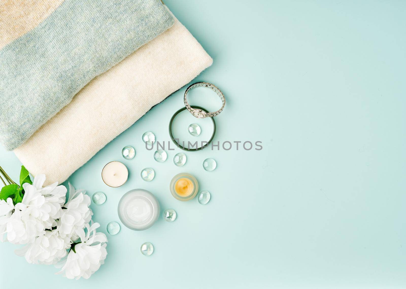 Flat lay woman accessories with cosmetic, facial cream on pastel blue table, copy space.