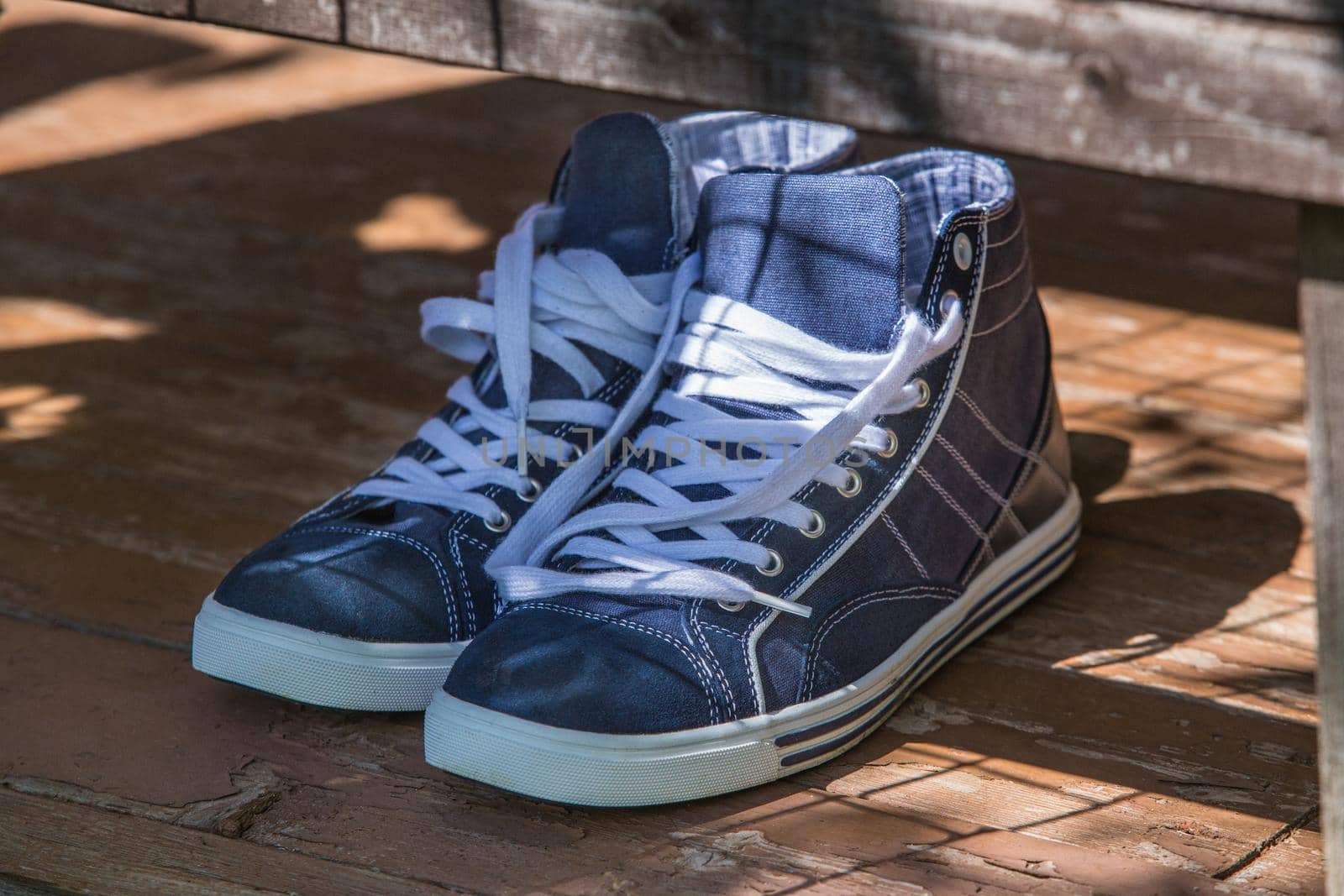 Men's blue denim sneakers on an old floor  by Yurii