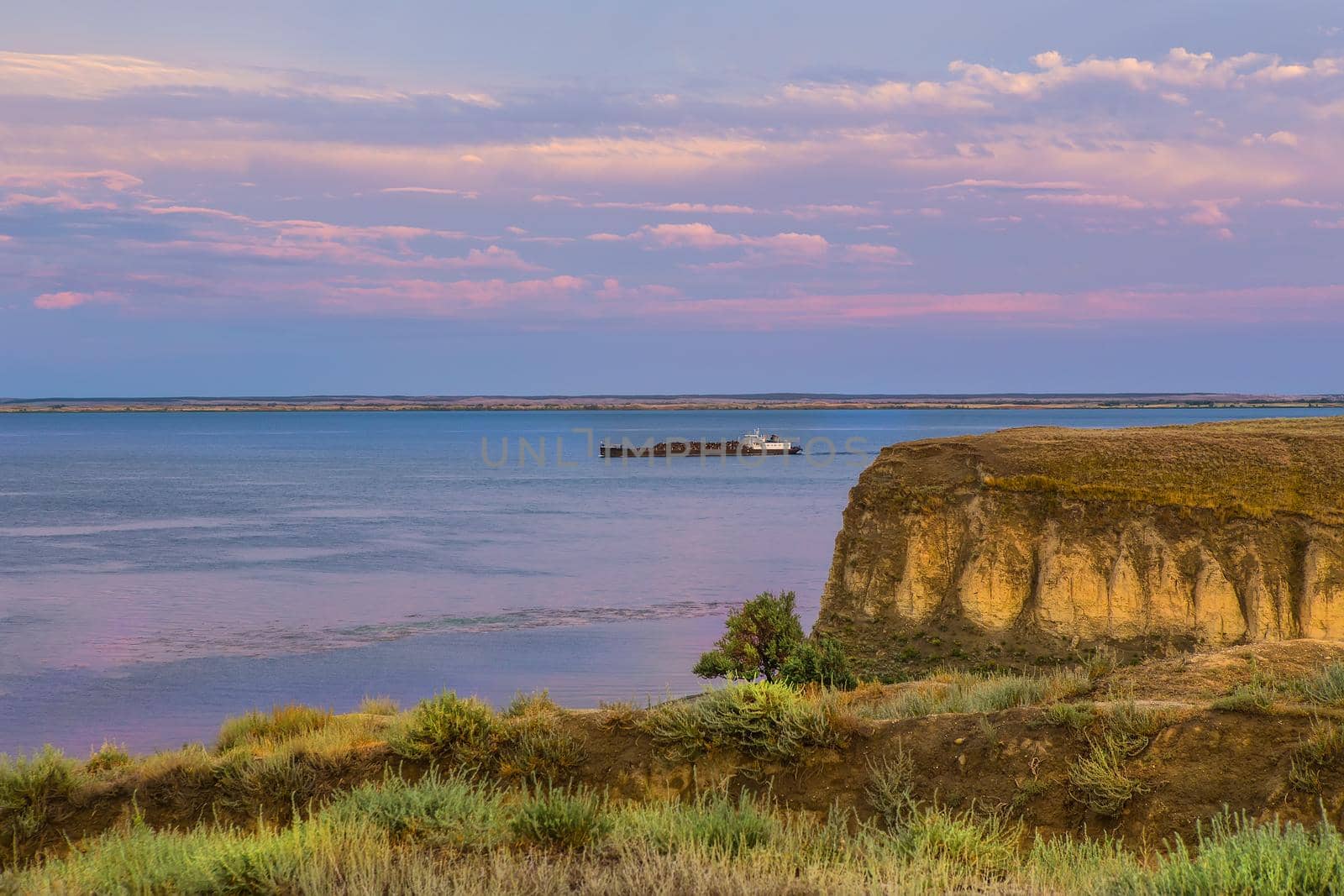 view of the Volga River from the high bank. Motor barge carrying cargo on the river.