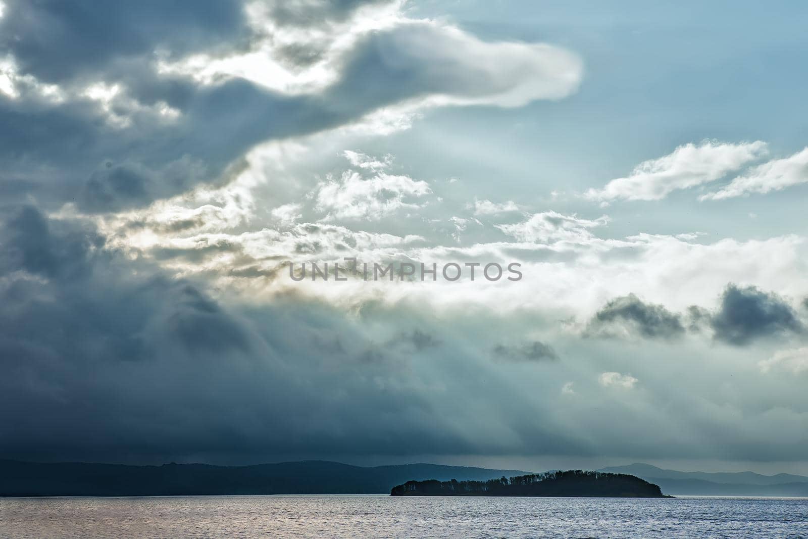 Calm sea and stormy clouds on mountainous background.