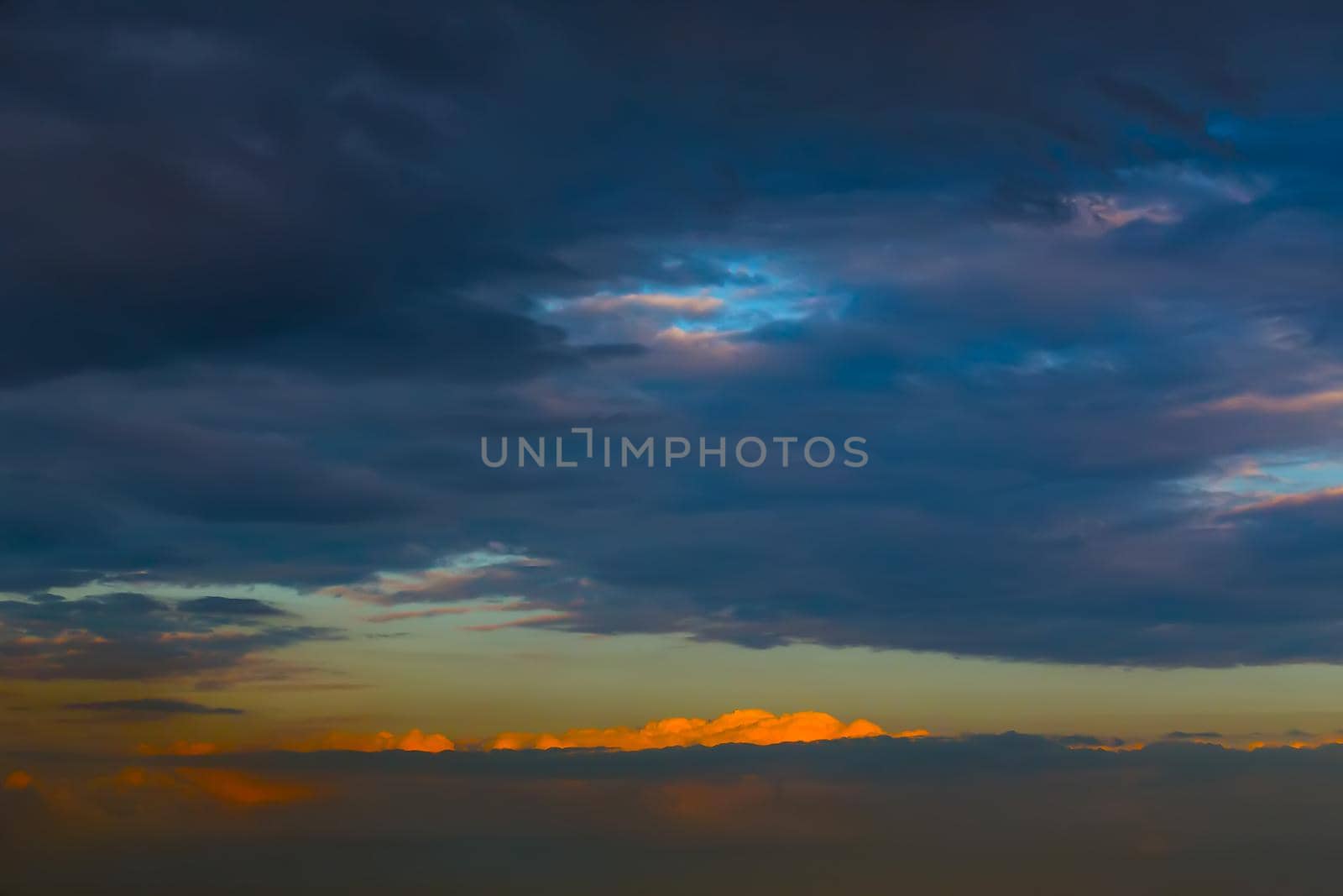 Last ray of the setting sun. Sky covered with dark blue clouds.